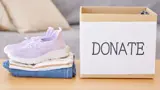 Clothes and shoes stacked up next to a box for donations.